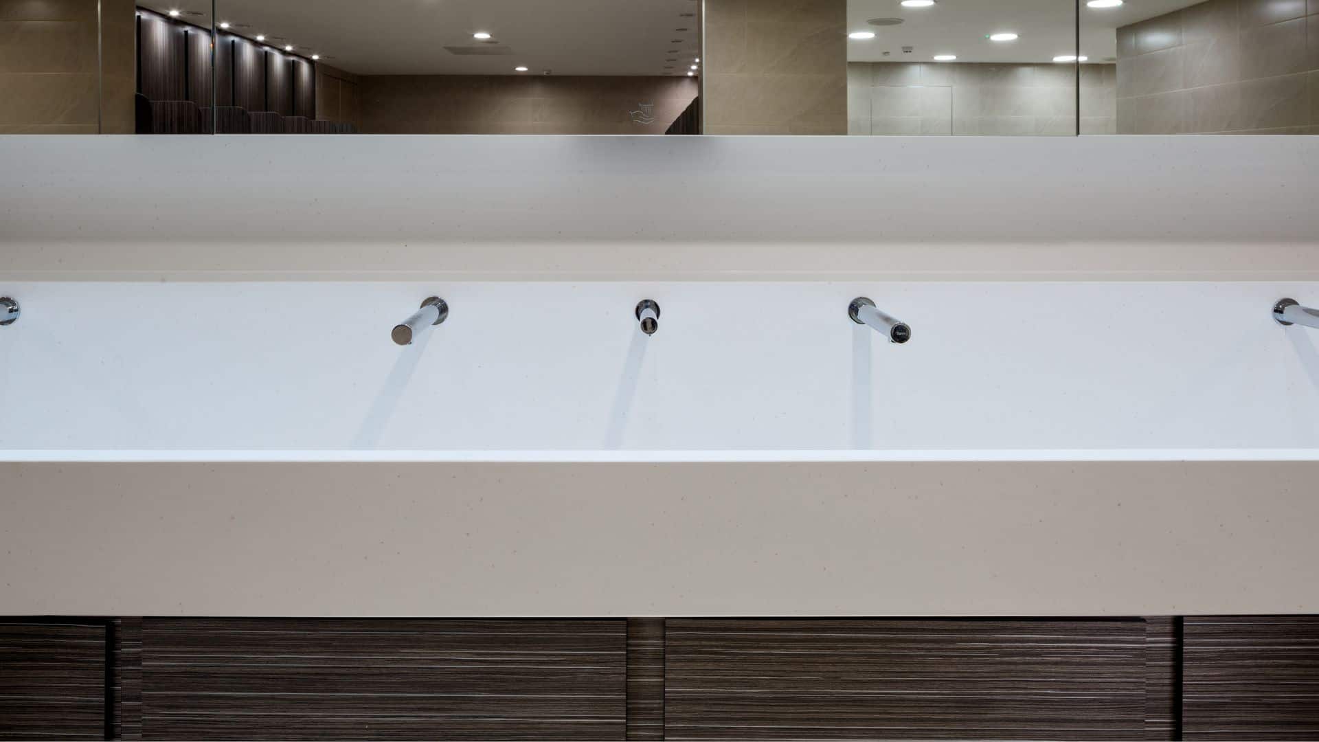 White Solid Surface Wash Trough with woodgrain underpanels in an industrial washroom