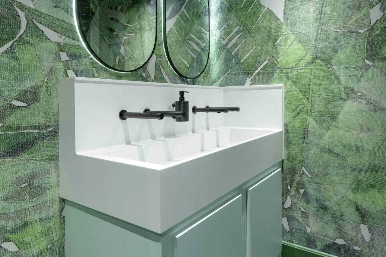 White Solid Surface Wash Trough with mint green underpanels in a sport and leisure washroom