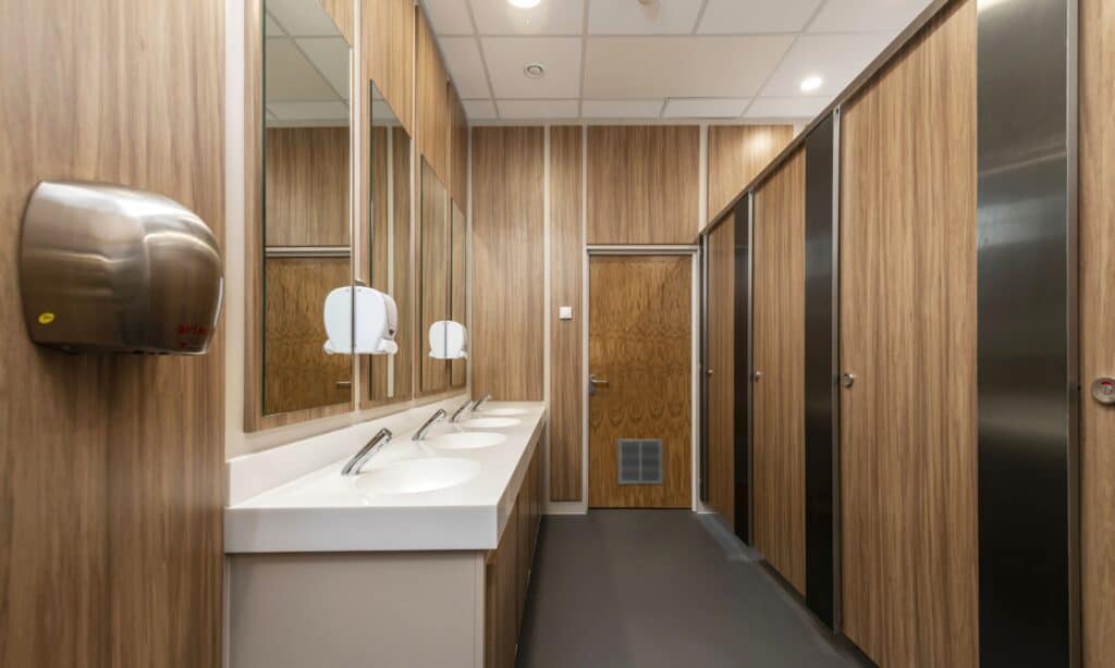 Reflect cubicles in a woodgrain finish in a school washroom with stainless steel pilasters