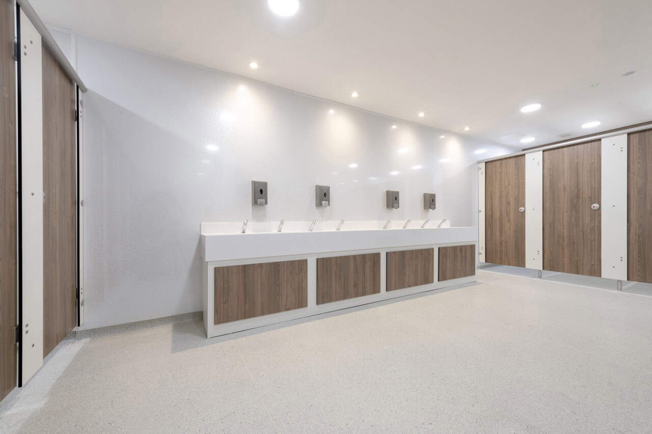 White Solid Surface Wash trough in a school washroom with woodgrain and white underpanels by Concept Washroom