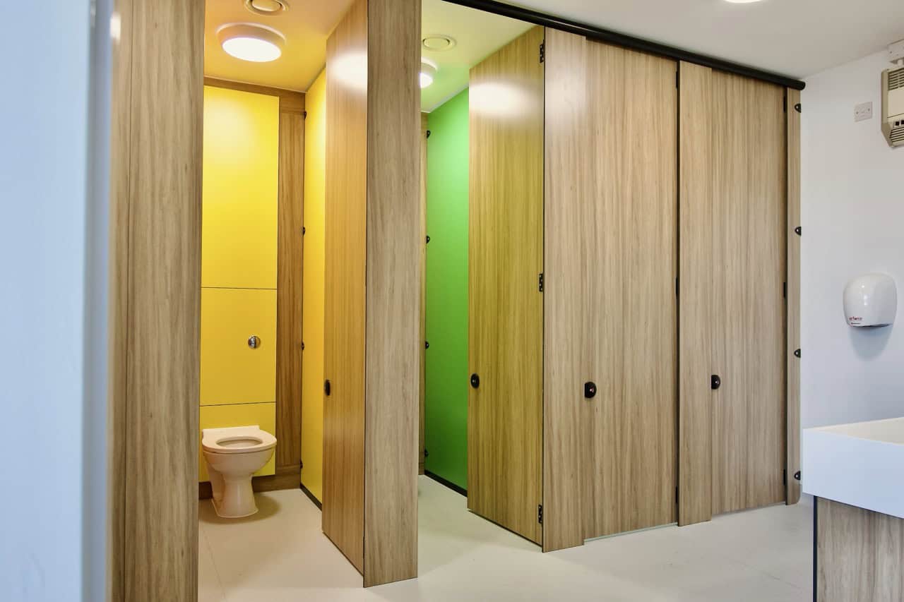 Row of full height Force Privacy cubicles by Concept Washroom with two cubicle doors open