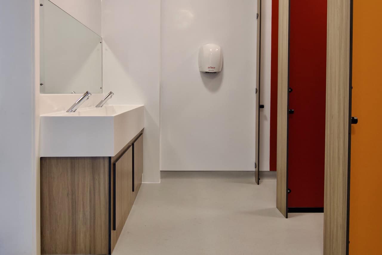 White Solid Surface Wash Trough in an Education Washroom with upstand and woodgrain underpanels