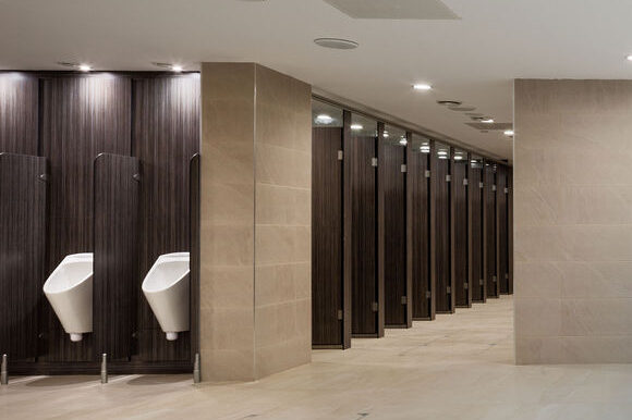 Modern transport washroom featuring Force Privacy cubicles and IPS in woodgrain laminate finish