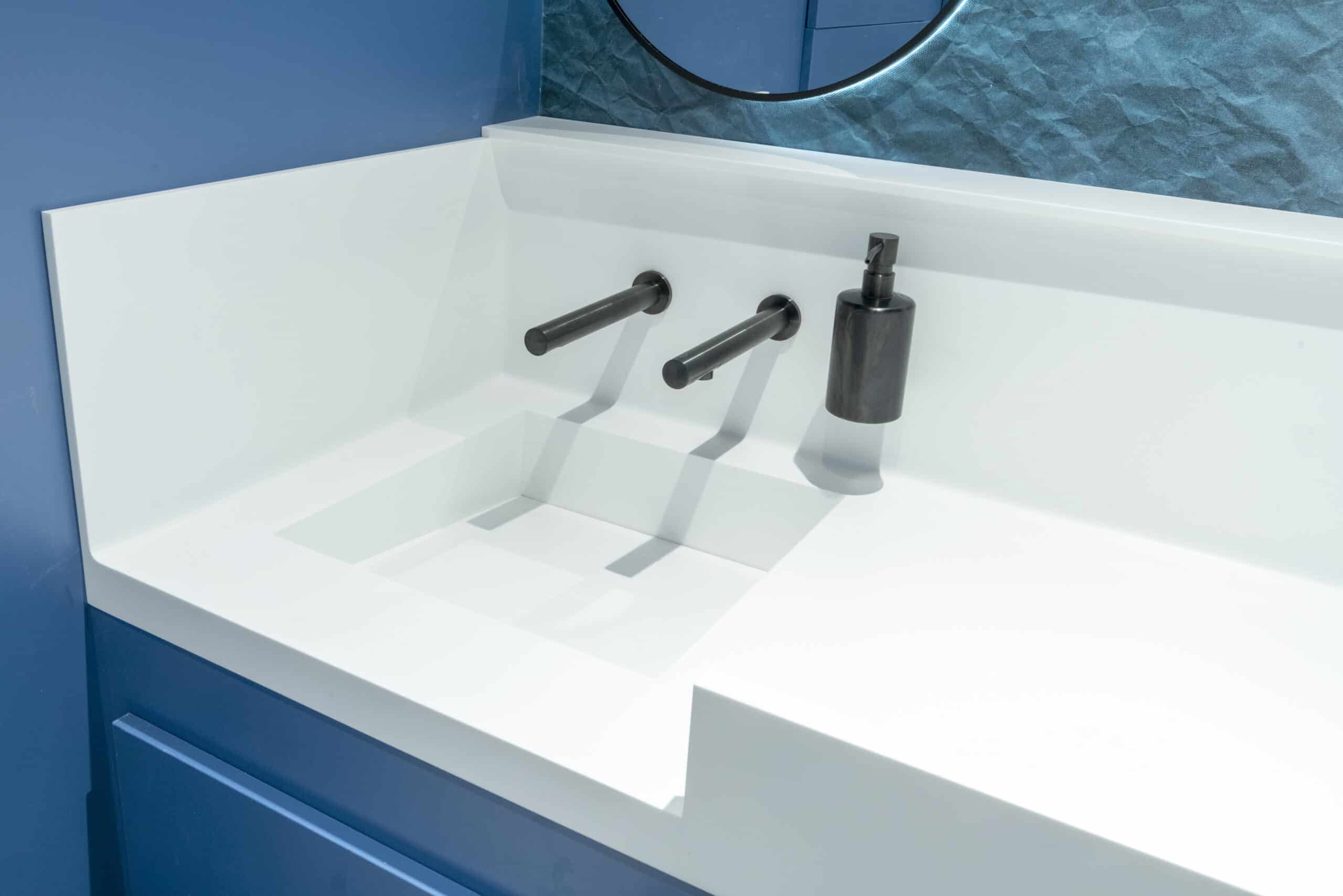 Modern solid surface vanity with sleek black faucet and minimalist design.