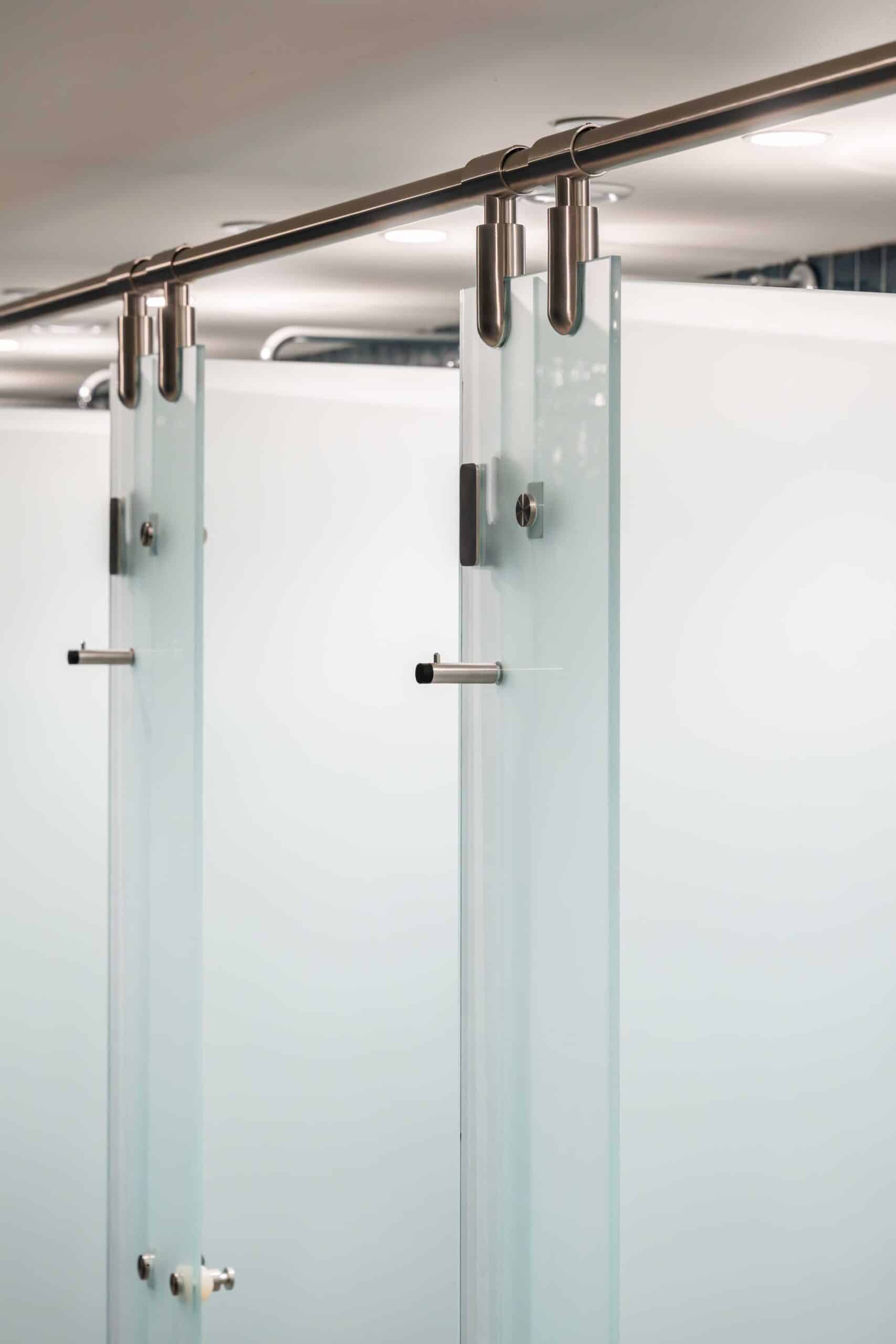 Glass shower cubicles with metal fixtures in a clean, modern washroom.