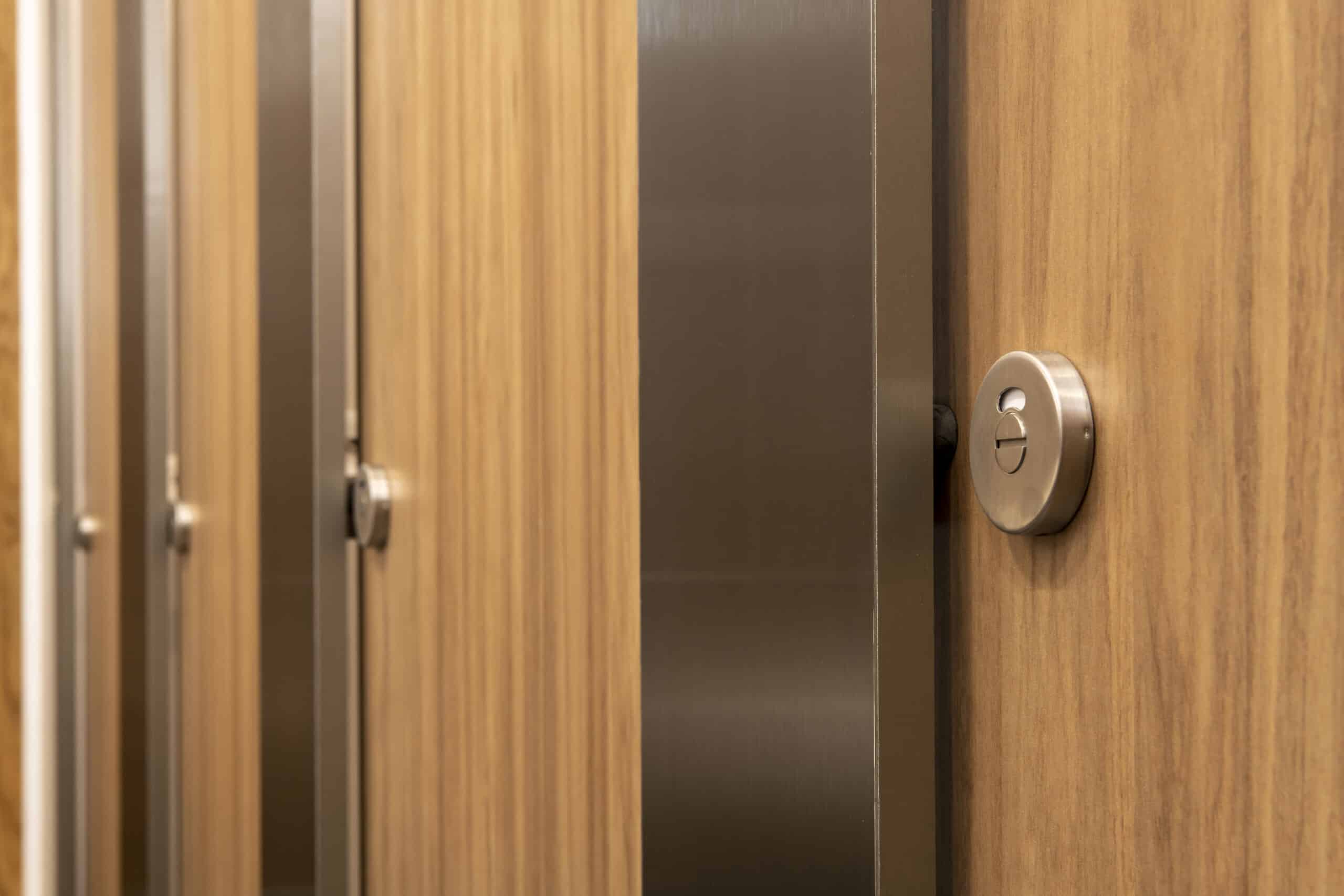 Reflect cubicles with a woodgrain finish and stainless steel pilasters in a school washroom