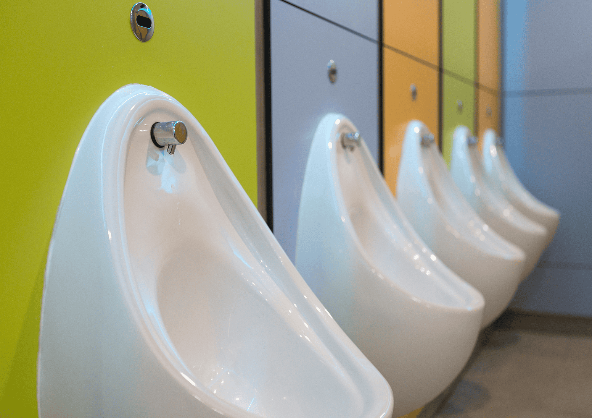 Urinals in a modern public restroom with vibrant coloured cubicles.