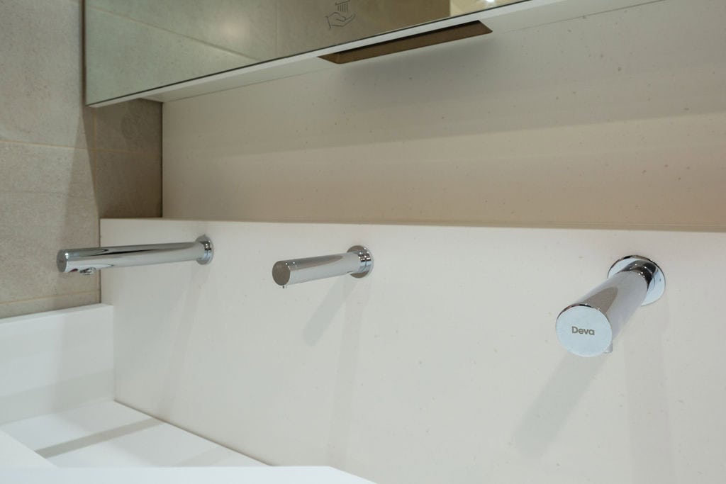 Solid Surface Wash Trough in a transport washroom with stainless steel wall-mounted taps
