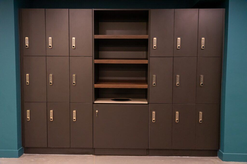 Row of dark grey lockers with open shelves in a public space.